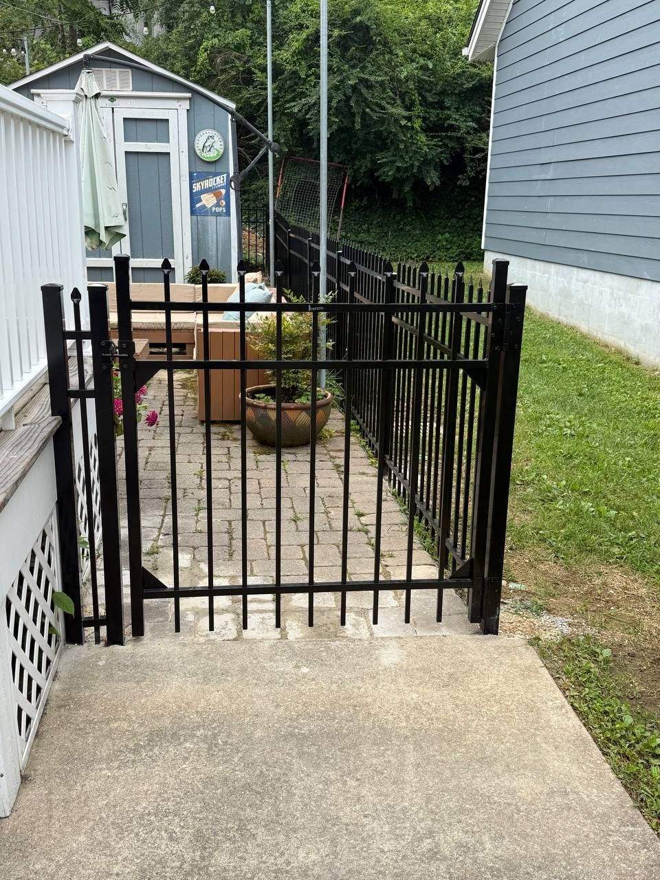 Black ornamental aluminum fence run following a grade change with a matching gate in Chattanooga, TN