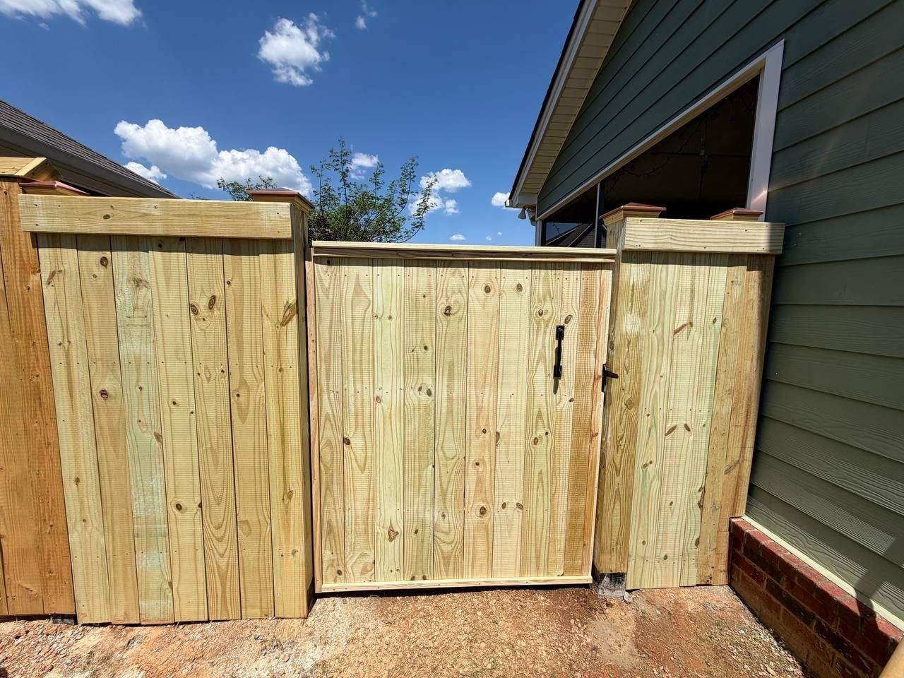 Newly installed pressure-treated wood privacy fence with capped posts and a custom gate in a Chattanooga backyard